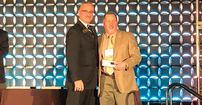 Head Athletic Trainer Bob Ward (right) poses on stage while being inducted into the Eastern Athletic Trainers Association Hall of Fame.