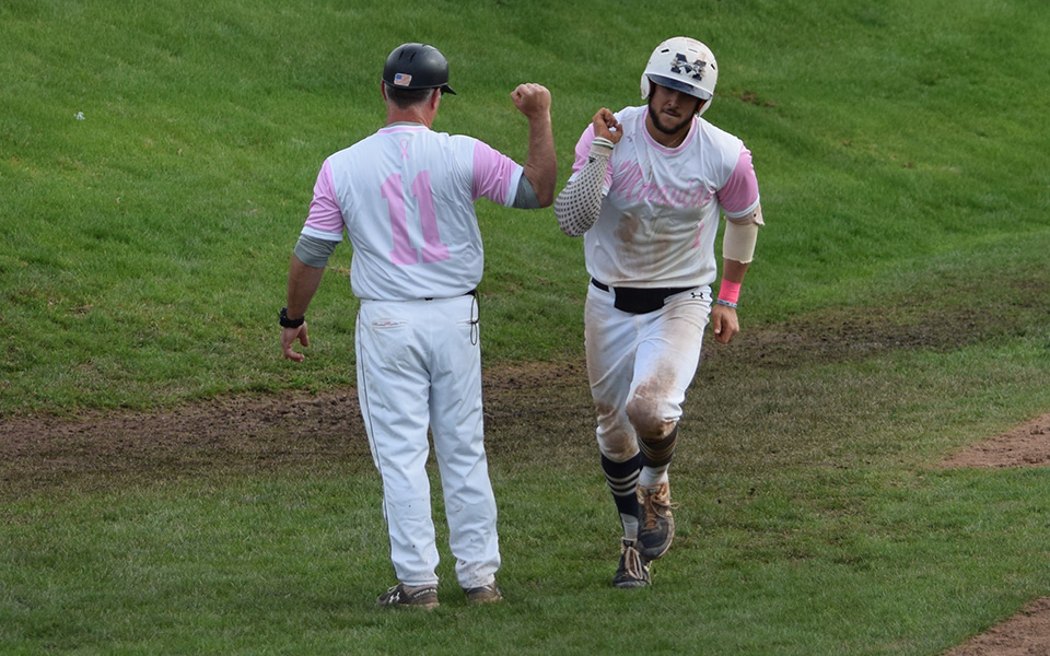 Senior Austin Markowski gets a high five from Head Coach Paul Engelhardt after rounding third base on his home run in the second game of a doubleheader versus The United States Merchant Marine Academy as the Greyhounds wore special pink jerseys for Breast Cancer Awareness Day at Gillespie Field.