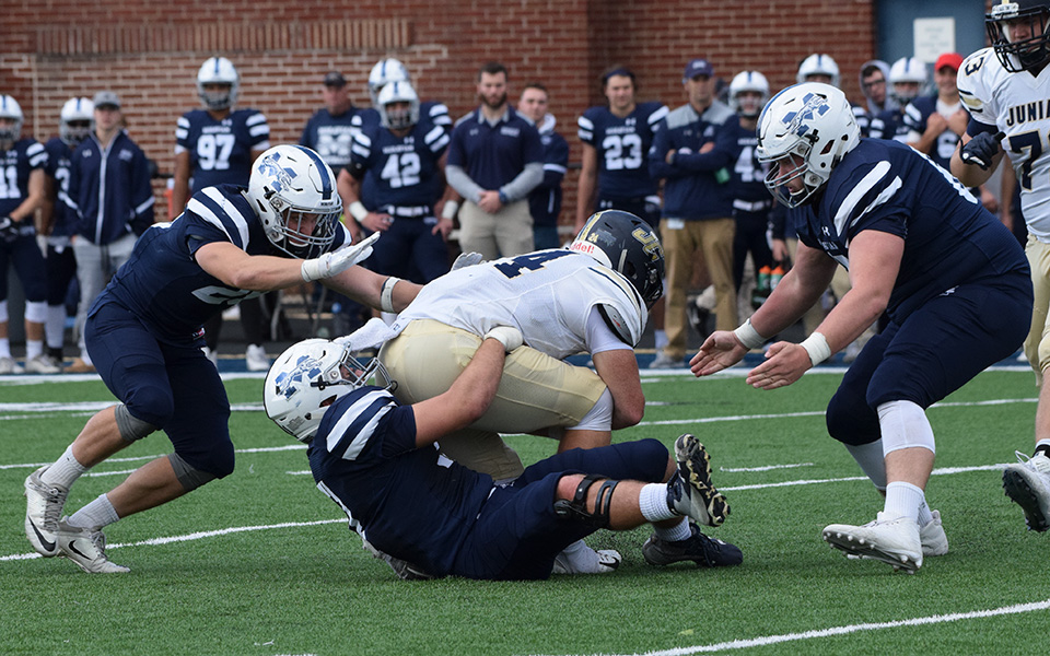 Dallas Owen, Nick Tone and Mike O'Hagan converge on the quarterback during the Juniata College game at Rocco Calvo Field.