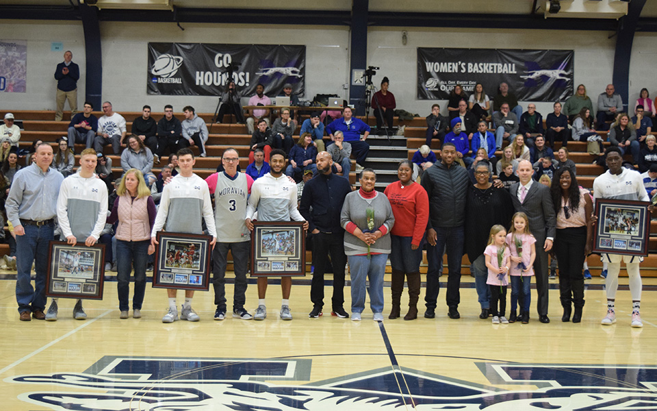 Seniors Will Brazukas, Nicholas Casazza, Oneil Holder and Jimmy Murray with their families and Head Coach Justin Potts and his daughters during the Senior Day presentation prior to tip-off versus Goucher College in Johnston Hall.