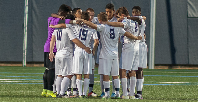 Men's Soccer squad huddles before a match in 2016