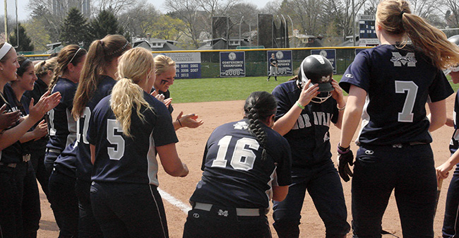 The Greyhounds greet junior Jenn Dalickas at home plate after her 11th home run of the season to break the single season record in the second inning of the second contest.