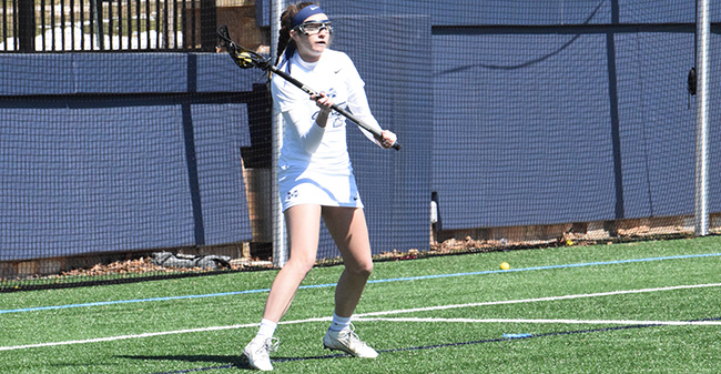 Kyleigh McGovern '18 looks to pass from behind the net in a match versus Juniata College in March 2018.