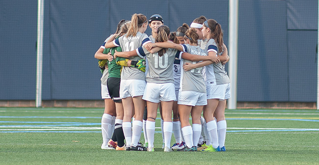 The women's soccer team huddles before its 2016 opener versus Arcadia University.