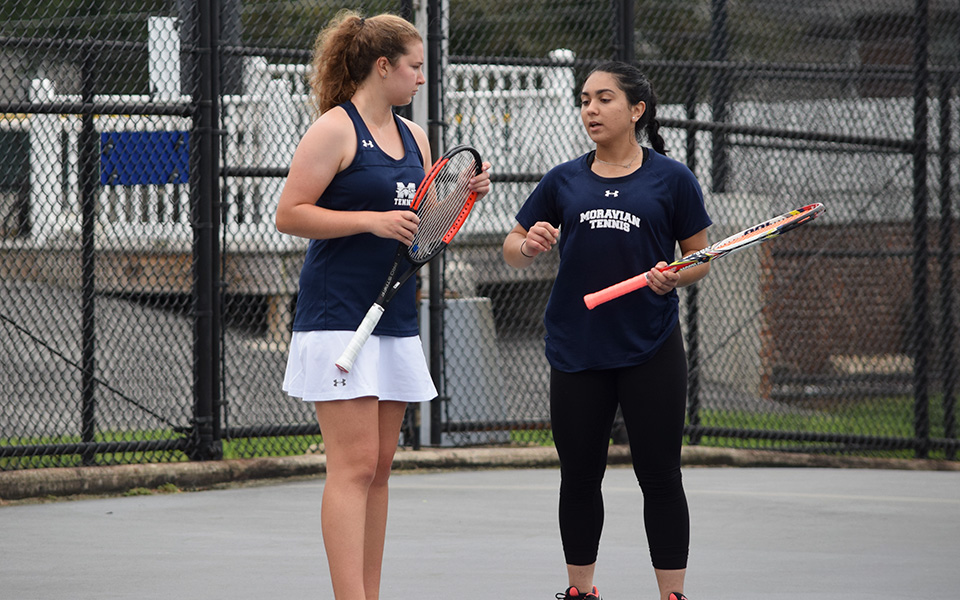 Sophomore Emma Angle and junior Eiman Nazif talk strategy in a doubles match versus Muhlenberg College on Hoffman Courts during the fall 2018 season.