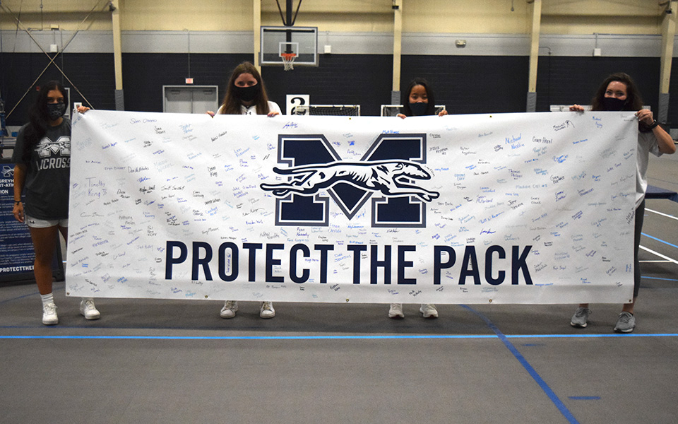 Members of the women's lacrosse team hold the Protect The Pack banner after the SAAC Kickoff event with over 300 signatures.