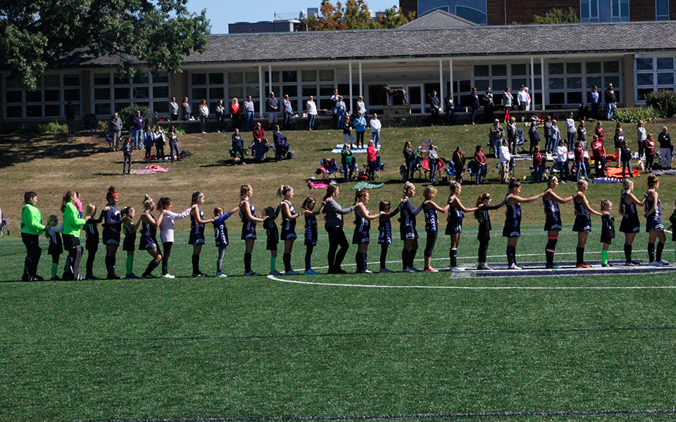 The Greyhounds get ready for the national anthem prior to their match versus Susquehanna University on John Makuvek Field with area youth field hockey players on Youth Day.