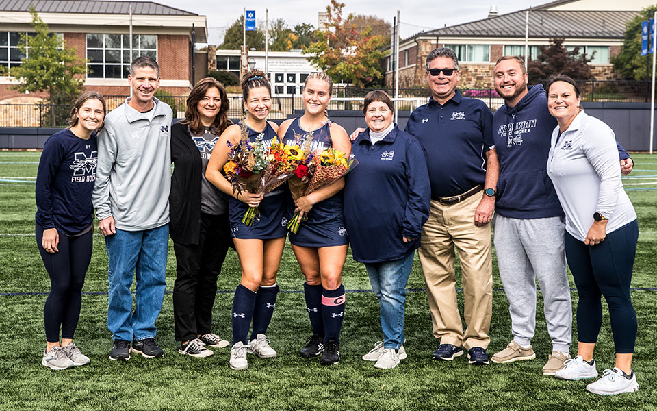 Seniors Ava Edwards and Emily Brandt with their parents and coaching staff on Senior Day.