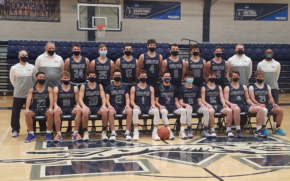 The 2020-21 men's basketball team photo in johnston hall wearing masks.