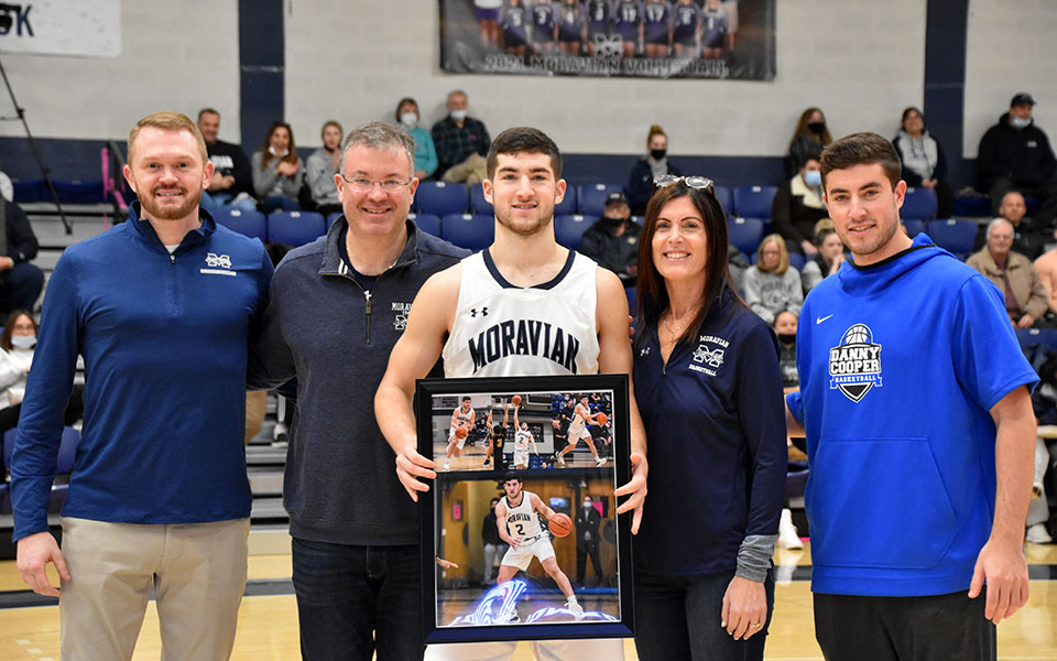 Senior guard Danny Cooper with his family and Head Coach Mike Frew '02 during the Senior Day festivities in Johnston Hall. Photo by Mairi West '23