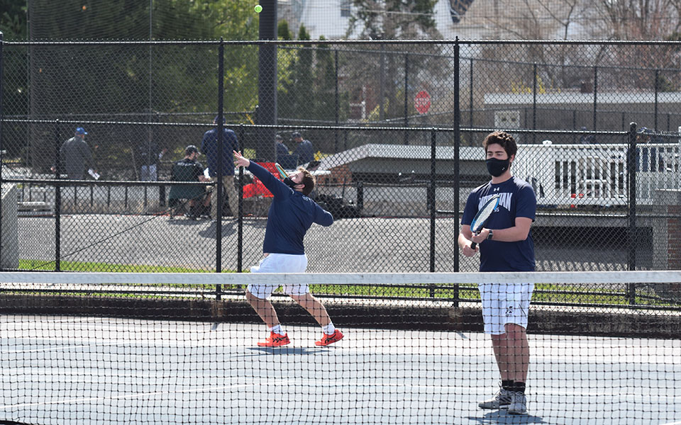 Kieran Pisani serves during a doubles match with Justin Szaro on Hoffman Courts during the 2021 spring season.