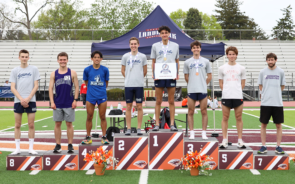 Graduate student Cole Stanchina stands atop the 10,000-meter run podium as the Greyhounds captured four of the top eight spots at the 2025 Landmark Conference Championships hosted by Susquehanna University. Photo by Rick Blair