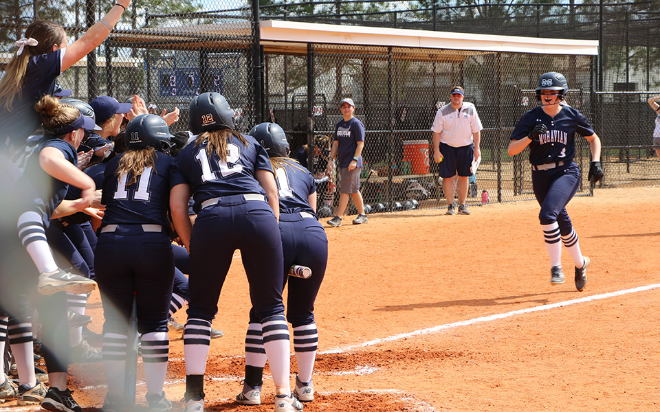 The Greyhounds greet junior Lauren Goetz at home plate after her first inning grand slam versus Thiel College at the Spring Games in Clermont, Florida.