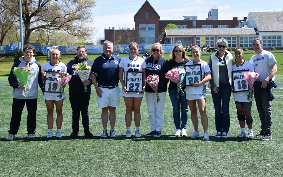 Seniors Olivia Williams, Keara Reilly, Alise Downey and Salome Carr with their families on Senior Day at John Makuvek Field. Photo by Marissa Williams '26