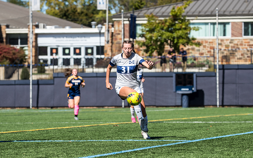 Senior midfielder Sydney DeFranco plays a ball upfield versus Lycoming College on John Makuvek Field this season. Photo by Cosmic Fox Media / Matthew Levine '11