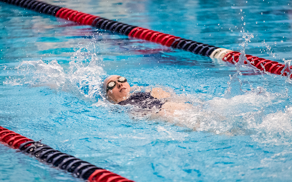 Junior Catie Lovett swims the backstroke in the 20o-yard medley relay during a meet at Liberty High School's Memorial Pool during the 2022-23 season. Photo by Cosmic Fox Media / Matthew Levine '11