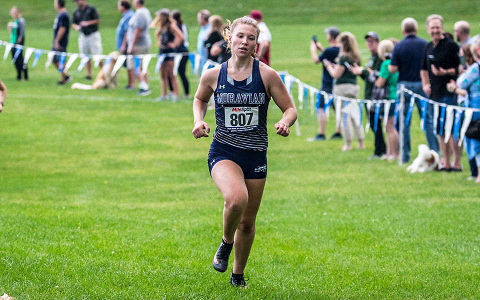 Amber Poniktera runs into the finish line at the 2021 Moravian Invitational at Bicentennial Park. Photo by Cosmic Fox Media / Matthew Levine '11.