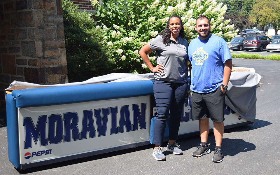 Moravian Assistant Athletic Director Rebecca May and William Allen High School Athletic Director Randy Atiyeh with the main scorer's table the Greyhounds donated to the Canaries.