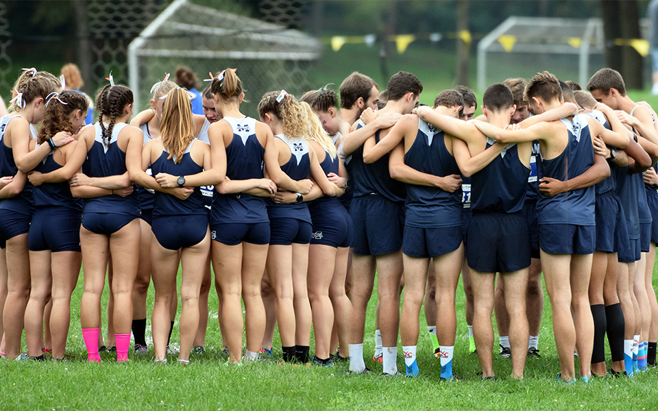the cross country squads huddle before the Moravian Invitational in 2019.
