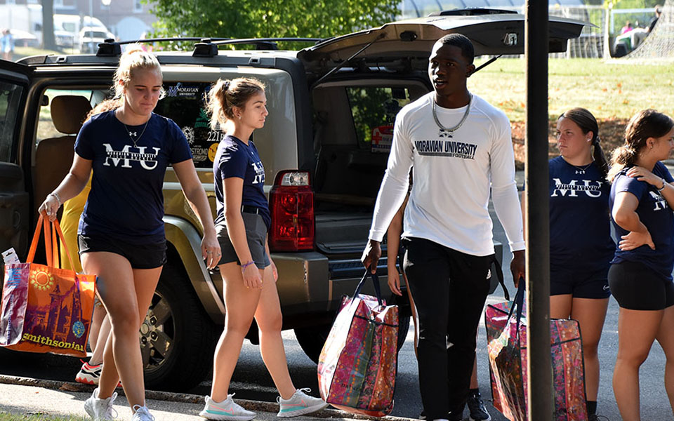 Field Hockey and Football student-athletes assisting in Freshman Move-In Day.